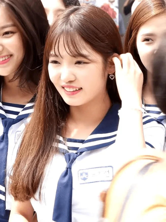 Jisun Noh in a school uniform, smiling as she adjusts her hair · Photographed in 2017